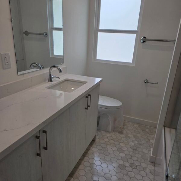 Bathroom vanity with a quartz top over a hexagon tile floor
