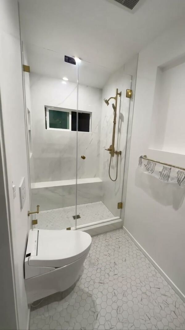 Shower in Altadena lined with porcelain slab, with a glass door and brass fixtures