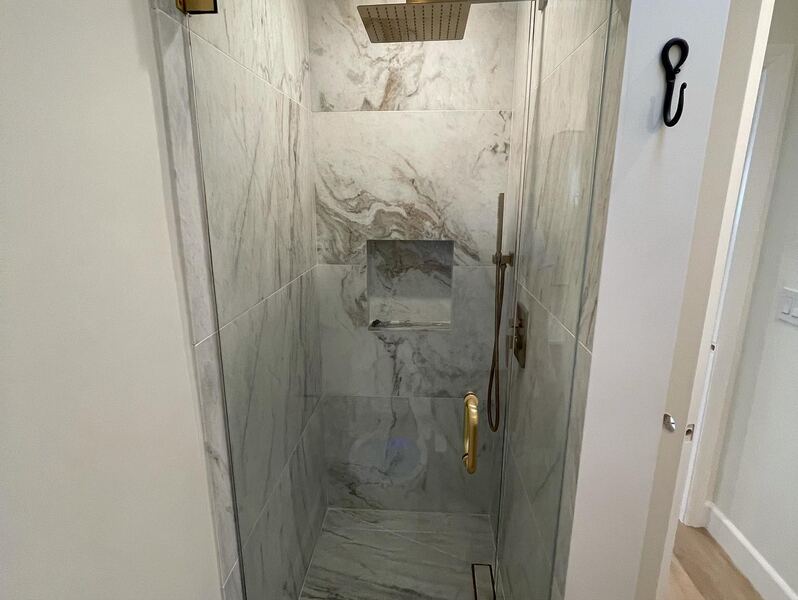 Marble-look tiled shower with brass fixtures