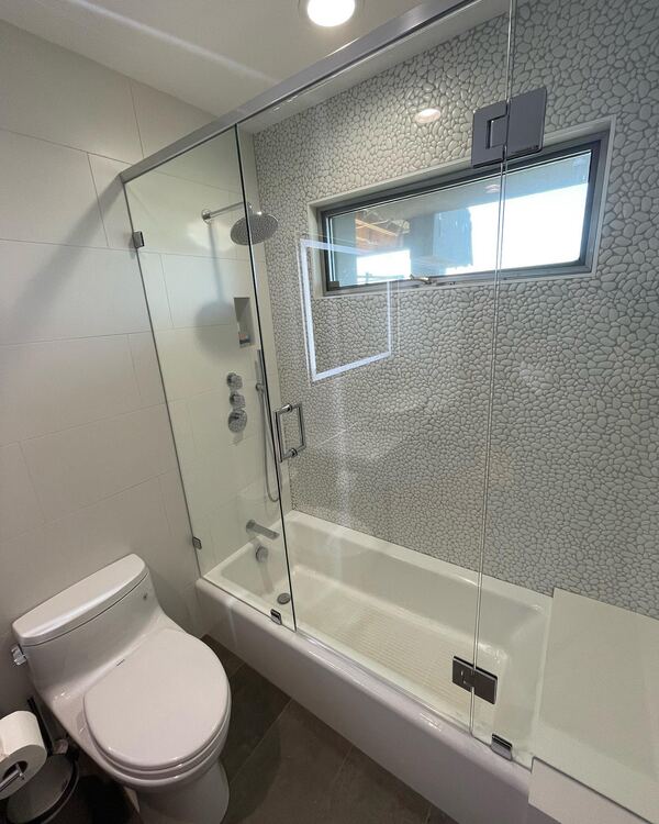 Tub with a frameless glass enclosure and a tiled wall