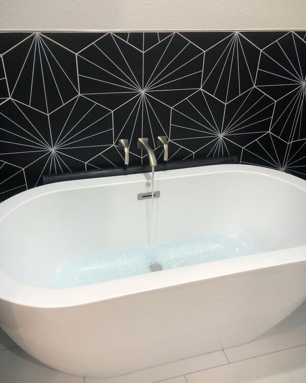 Freestanding tub in Monrovia against a black and white patterned tile wall