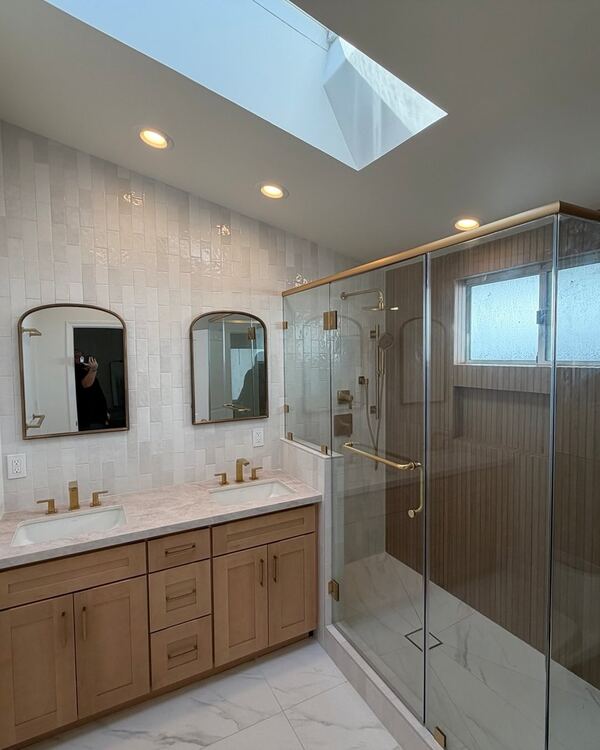Remodeled bathroom in Pasadena with a skylight, double vanity and glass shower